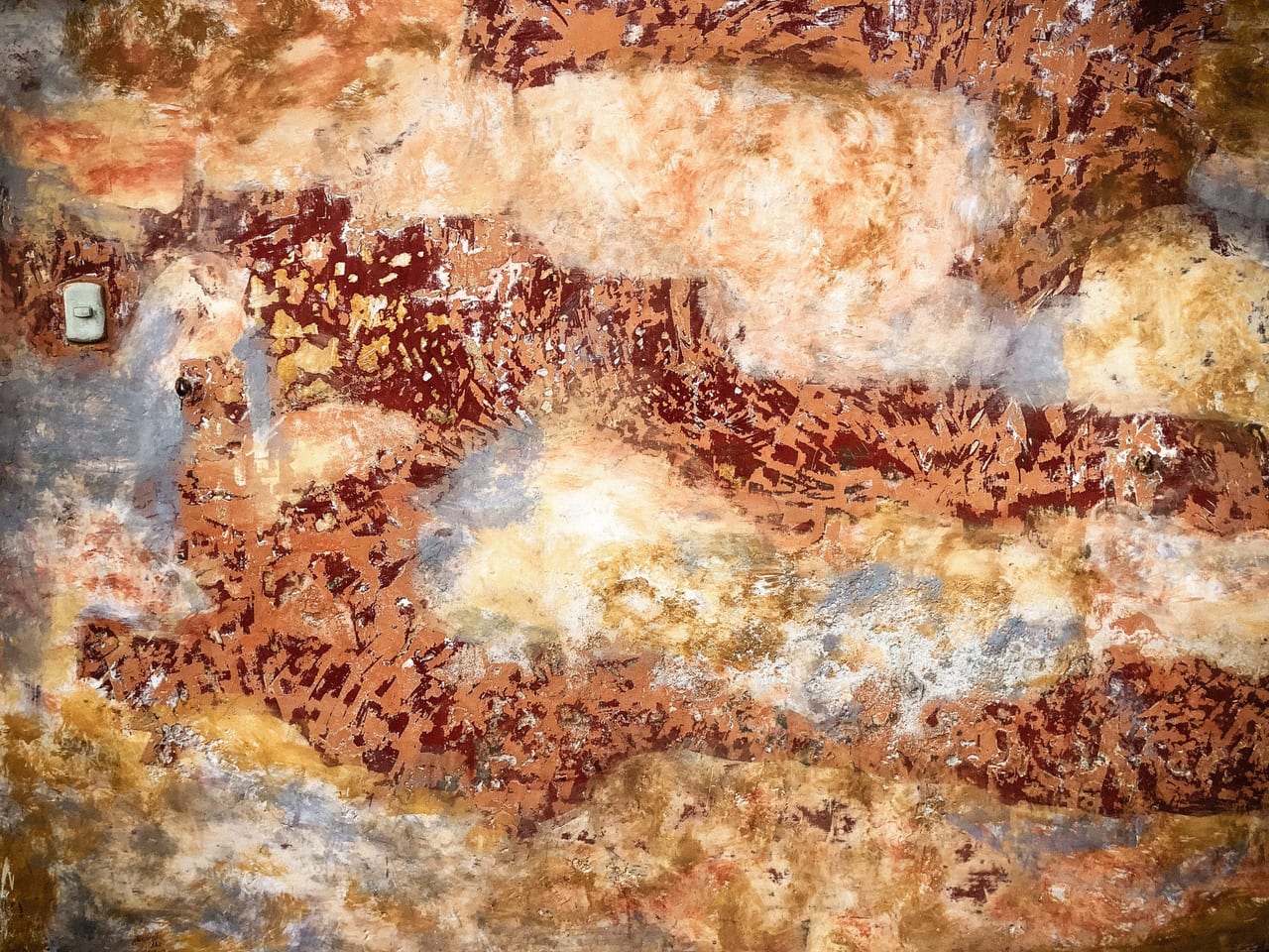 Rust-red plaster eroding into blue