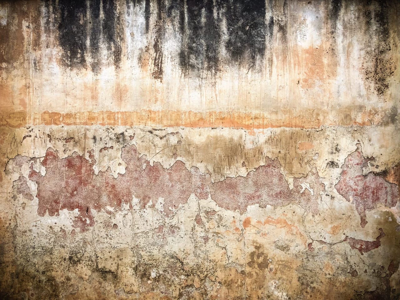 A stained cream wall dripping dark at the top