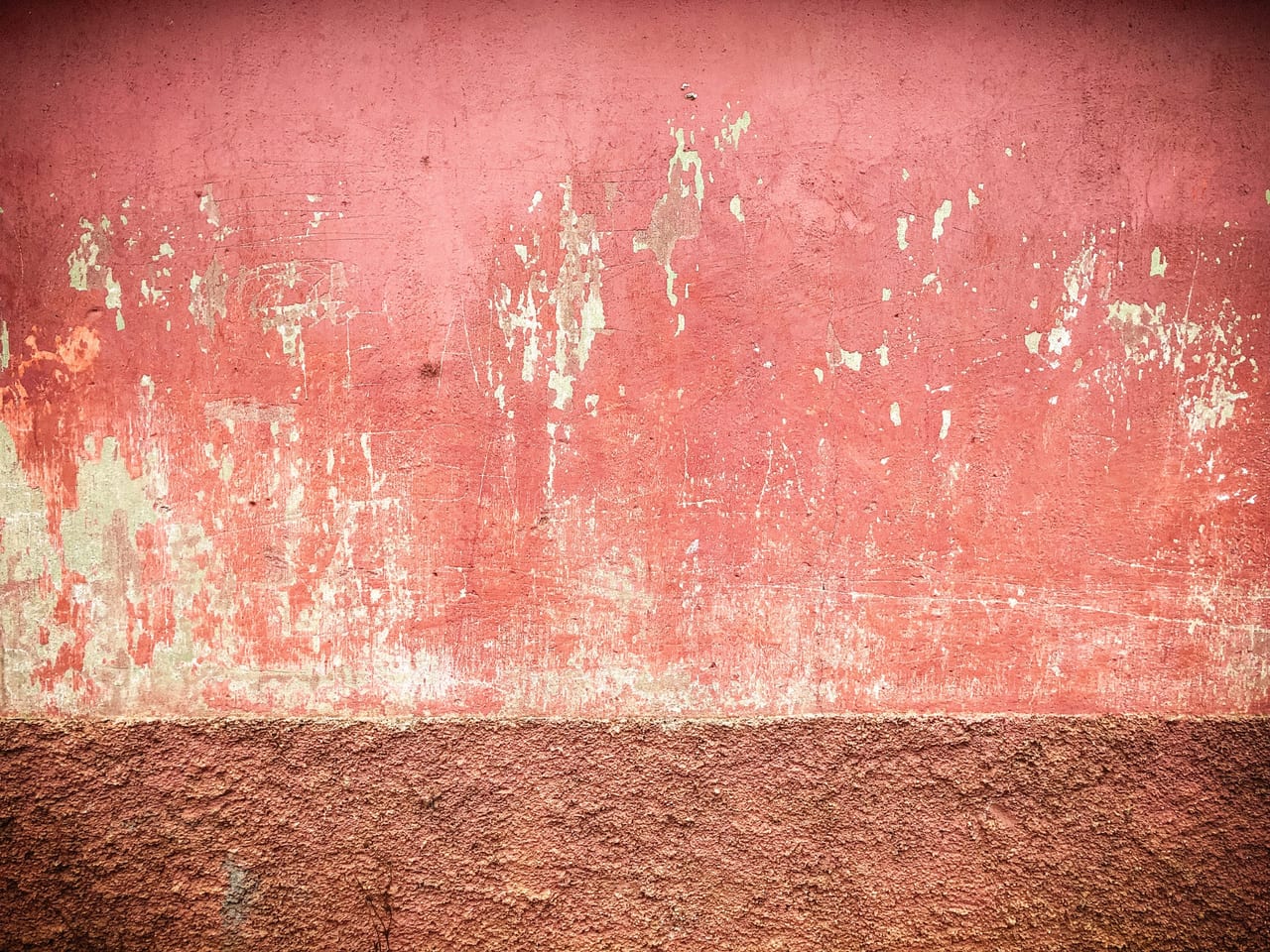 A faded red wall above a darker plinth