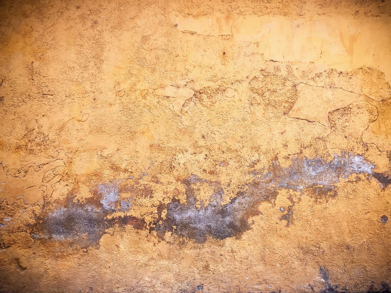 An ochre wall with a dark blue scar