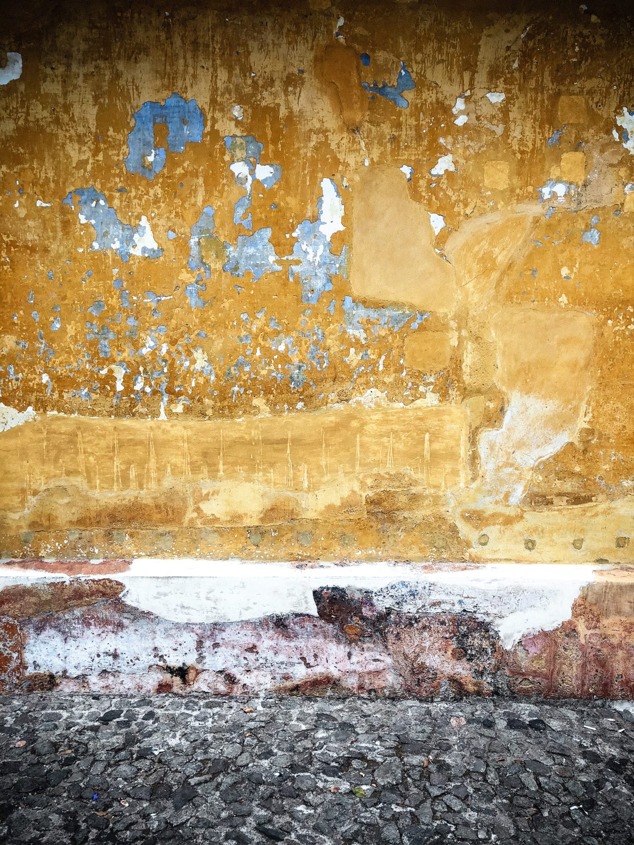 Ochre and blue plaster above a cobbled street