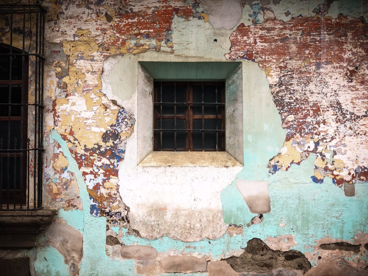 A small barred window in patched plaster