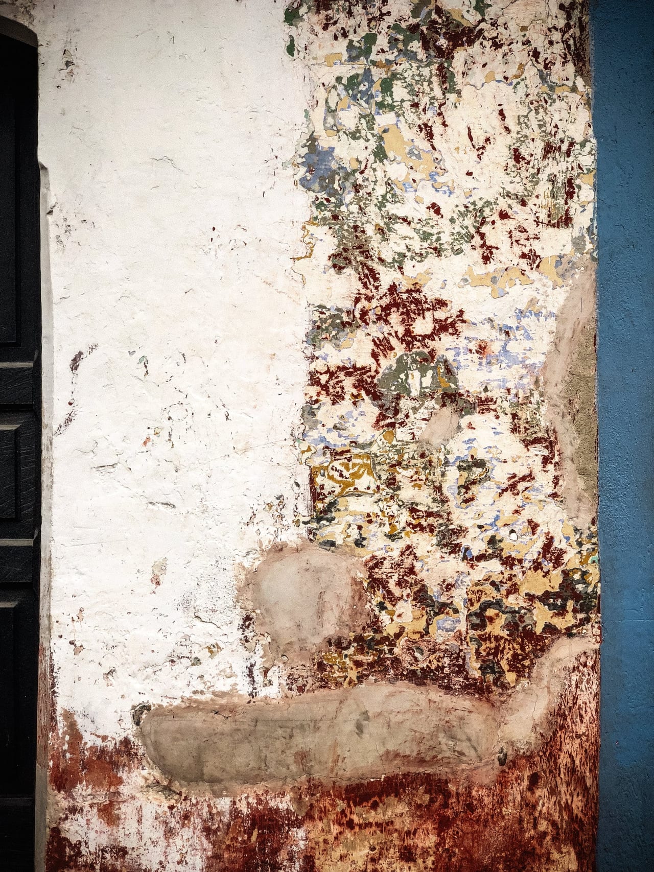 A narrow strip of crumbling wall between blue and black