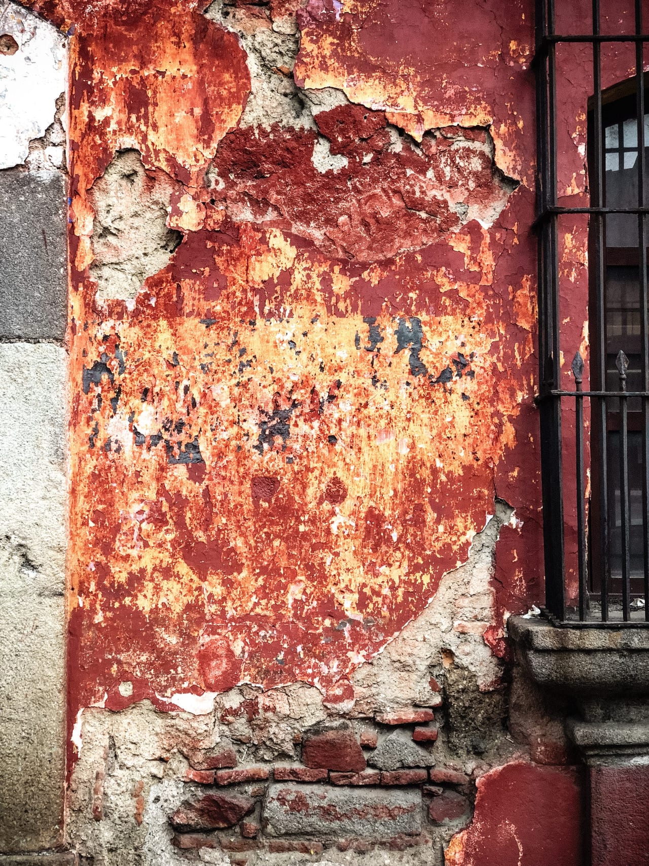 Rust and old paint around a barred window