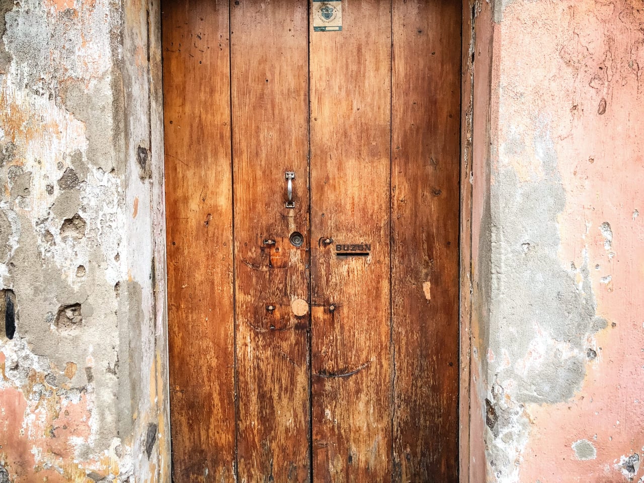 A wooden door set into a pink wall