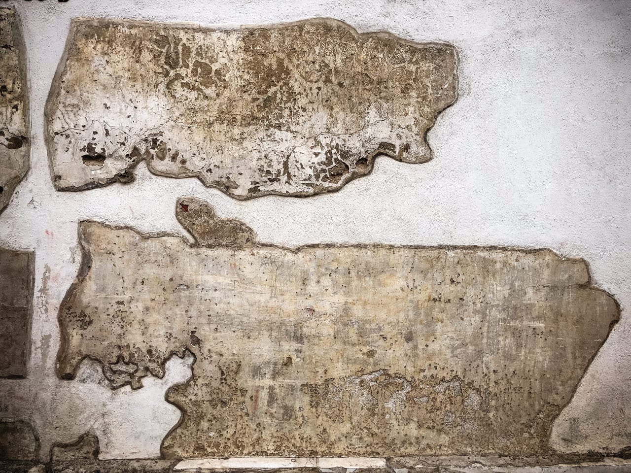 Plaster islands floating on a pale wall