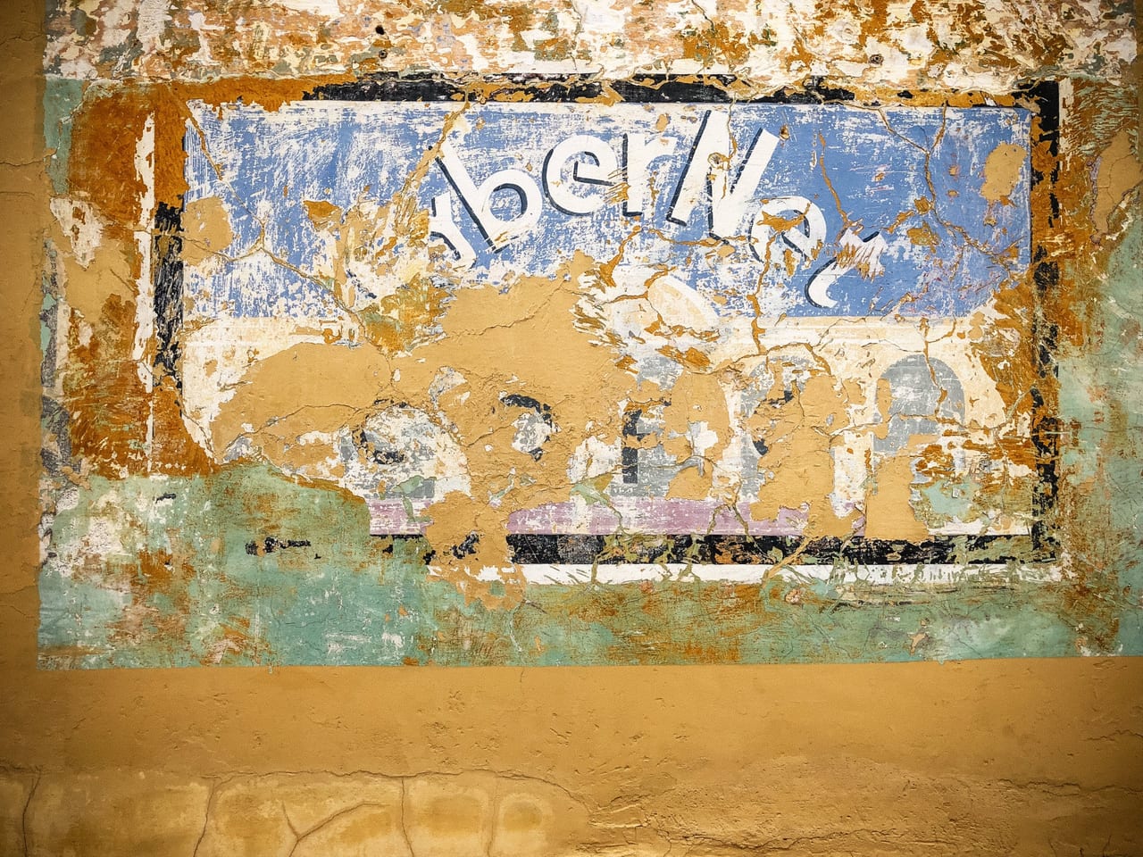 A faded hand-painted sign on an ochre wall