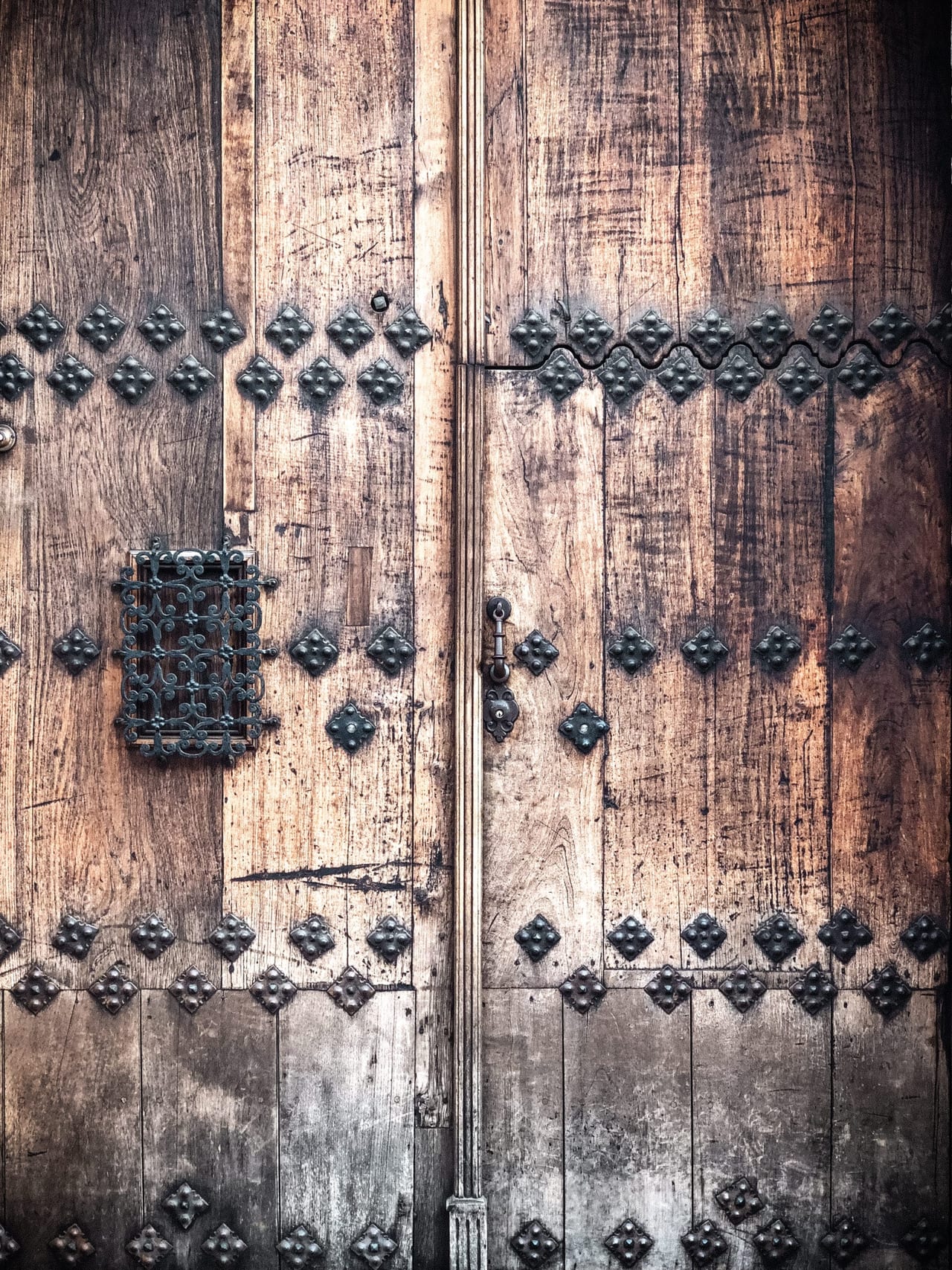 A studded wooden door with a small grille